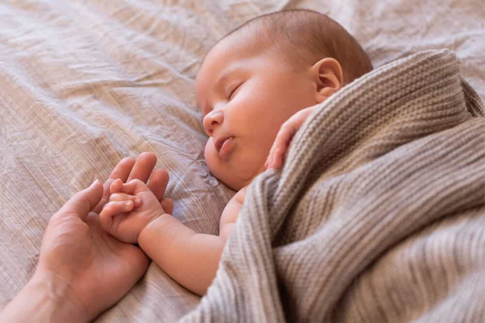Por que o bebê fica com as mãos fechadas?