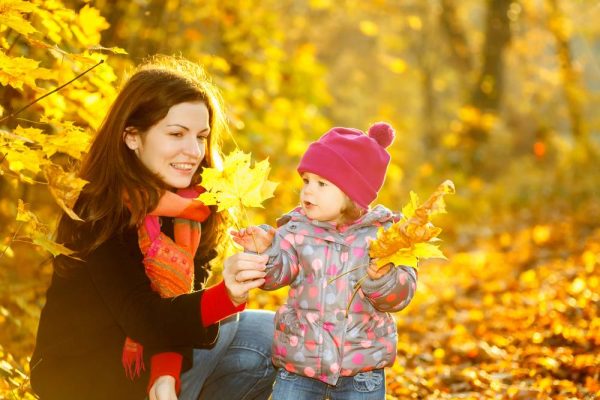 mãe e filha brincando com folhas no outono