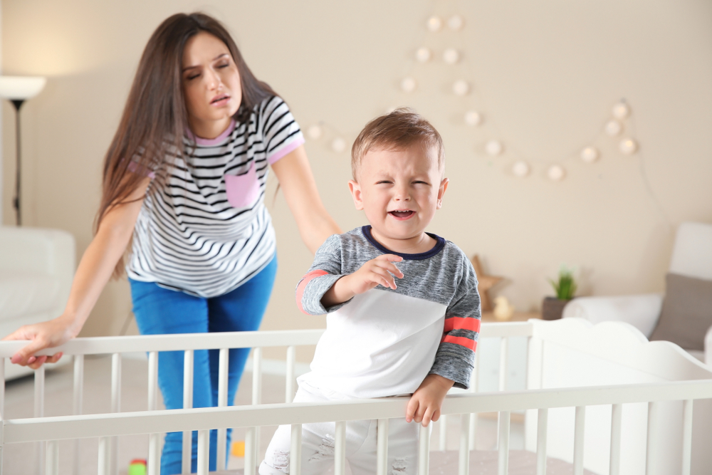 bebê chorando no berço, mãe assiste confusa